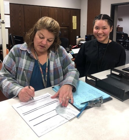 Duyen Nguyen, senior, and her instructor, Mrs. Summeier, finish Duyen's application to become a licensed cosmetologist.